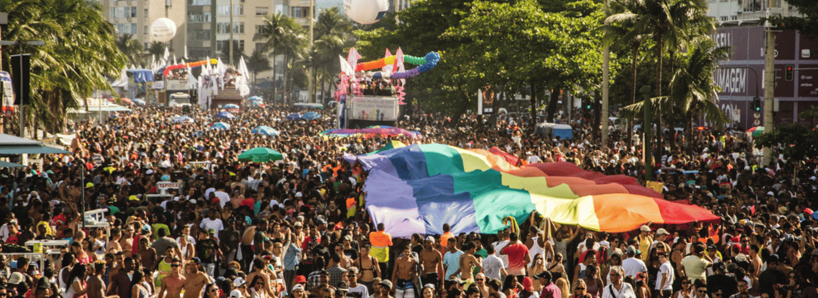 Multidão na Parada do Orgulho LGBTI+ Rio com a bandeira do arco-íris